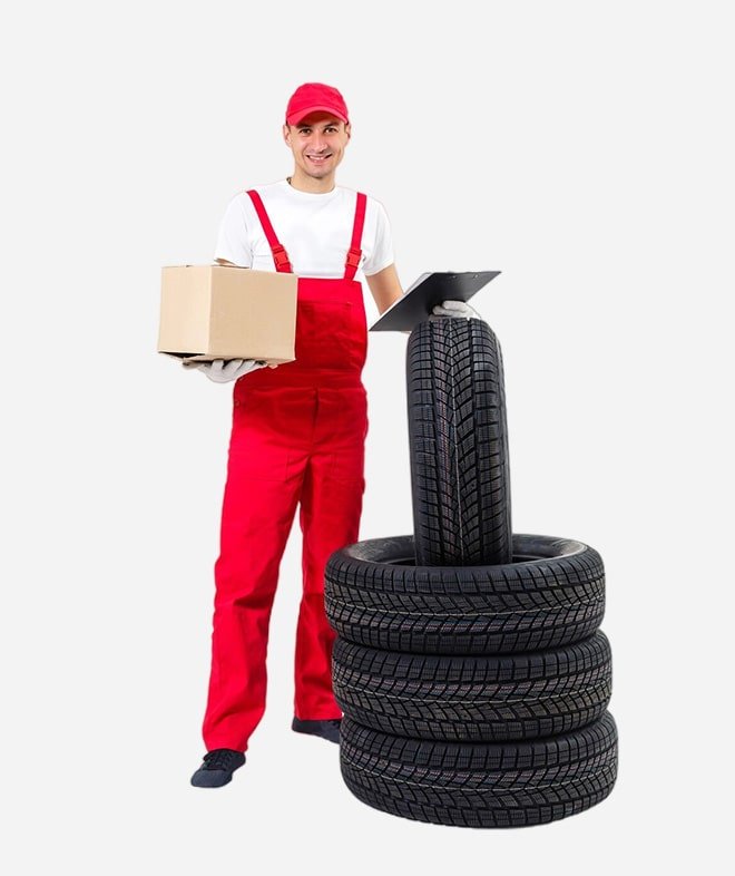 a mechanic in a red uniform with a stack of tires and a cardboard box.